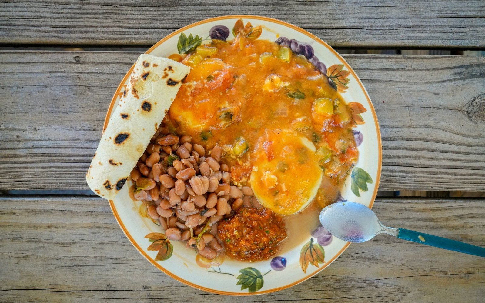 Plate of eggs in tomato broth with pinto beans and a charred flour tortilla